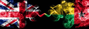 İngiltere vs Gine Bissau dumanlı mistik bayrakları yan yana yerleştirilmiş. Büyük Britanya ve Gine Bissau ipeksi duman bayrakları renkli kalın.