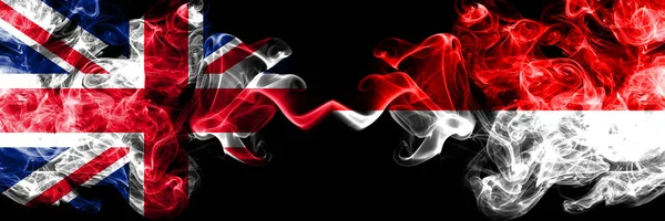 Royaume-Uni vs Indonésie, drapeaux mystiques fumés indonésiens placés côte à côte. Drapeaux de fumée soyeux de couleur épaisse de Grande-Bretagne et d'Indonésie, Indonésien . — Photo