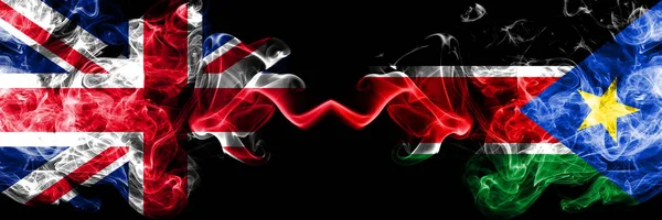 Velká Británie vs Jižní Súdán zakouřený mystic vlajky umístěné vedle sebe. Silný barevný hedvábně kouře vlajky Velké Británie a Jižní Súdán. — Stock fotografie