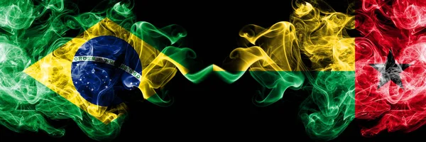 Brasile vs Guinea Bissau bandiere fumogene affiancate. Bandiere di fumo spesse colorate e setose del Brasile e della Guinea Bissau — Foto Stock
