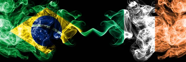 Brazylia vs Irlandia, irlandzkie flagi dymu umieszczone obok siebie. Grube kolorowe, jedwabiste flagi dymu brazylijskiego i Irlandii, irlandzkiego — Zdjęcie stockowe