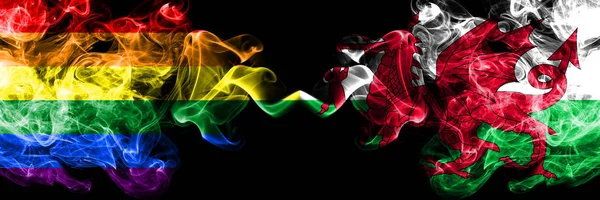 Gay VS Wales, Welsh rook vlaggen naast elkaar geplaatst. Dikke gekleurde zijdeachtige rook vlaggen van Pride en Wales, Welsh — Stockfoto