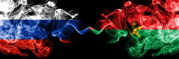 Banderas rusas vs Burkina Faso colocadas una al lado de la otra. Banderas de humo sedoso de color grueso de Rusia y Burkina Faso — Foto de Stock