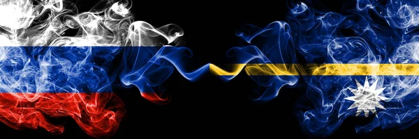 Русские vs Nauru дымят флагами, расположенными рядом. Толстые шёлковые дымовые флаги России и Науру — стоковое фото