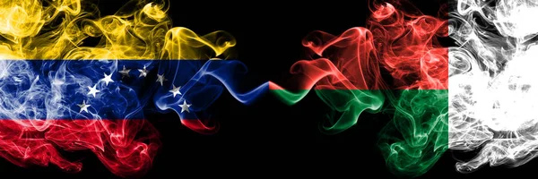 Venezuela vs Madagascar, drapeaux mystiques fumés malgaches placés côte à côte. Drapeaux de fumée soyeuse de couleur épaisse du Venezuela et de Madagascar, Madagascar — Photo