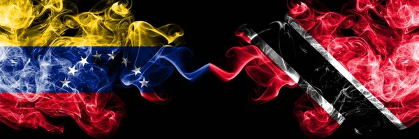 Venezuela vs Trinidad and Tobago smoky mystic flags placed side by side. Thick colored silky smoke flags of Venezuela and Trinidad and Tobago