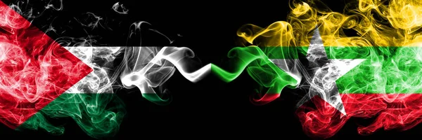 Filistin vs Myanmar dumanlı mistik bayraklar yan yana yerleştirilir. Kalın renkli ipeksi Filistinliler ve Myanmar bayrağı dumanlar