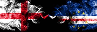 İngilizce vs Cape Verde dumanlı mistik bayraklar yan yana yerleştirilir. Kalın renkli ipeksi İngiltere ve Cape Verde bayrağı dumanlar.