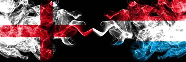 Engelska vs Luxembourg rökig Mystic flaggor placerade sida vid sida. Tjocka färgade silkeslena röker flagga av England och Luxemburg. — Stockfoto