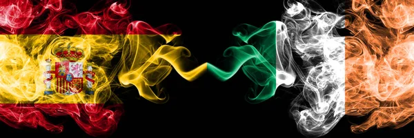 Spanien mot Irland, irländska rökiga mystiska flaggor placerade sida vid sida. Tjocka färgade silkeslena röker flagga spanska och Irland, irländska — Stockfoto