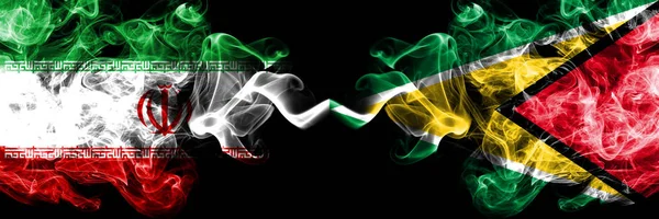 イラン vs ガイアナ, ガイアナスモーキー神秘的な状態フラグが並んで配置.イランとガイアナ、ガイアナの濃い色の絹のような煙の旗の組み合わせ — ストック写真