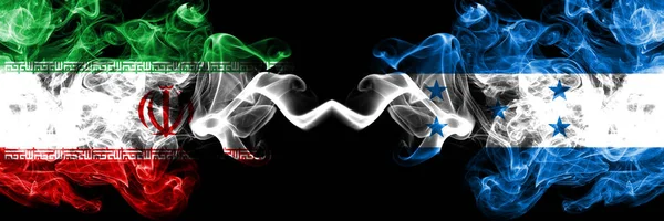 Irán vs Honduras, banderas hondureñas de estados místicos ahumados colocadas una al lado de la otra. Bandera de humo sedoso de color grueso combinación de Irán y Honduras, Honduras —  Fotos de Stock