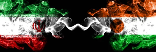 Iran VS Niger, Nigeriaanse rokerige Mystic Staten vlaggen geplaatst naast elkaar. Dikke gekleurde zijdeachtige rookt vlag combinatie van Iraanse en Niger, Nigeriaanse — Stockfoto