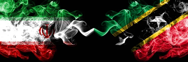 Iran vs Saint Kitts and Nevis smoky mystic states flags placed side by side. Thick colored silky smokes flag combination of Iranian and Saint Kitts and Nevis