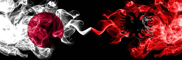 Japan vs Albanien, Albanska rökig Mystic flaggor placerade sida vid sida. Tjocka färgade silkeslena röker kombination av Albanien, albanska och japanska flaggan — Stockfoto