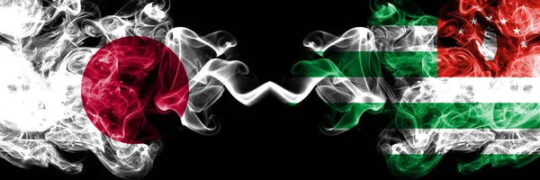 Japan vs abkhazia, abchasische rauchige mystische Flaggen nebeneinander. dicke, seidige Rauchschwaden Kombination aus abchasischer, abchasischer und japanischer Flagge — Stockfoto