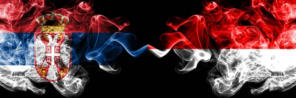 Serbia vs Indonesia, bandiere mistiche fumose indonesiane affiancate. Combinazione di fumi setosi di colore spesso di Serbia e Indonesia, bandiera indonesiana — Foto Stock