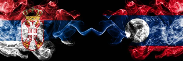 Serbia vs Laos smoky Mystic flagi umieszczone obok siebie. Grube kolorowe jedwabiste pali połączenie flagi serbskiej i Laosu — Zdjęcie stockowe
