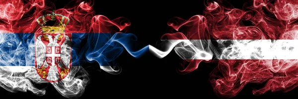 Serbia vs Latvia, Latvian smoky mystic flags placed side by side. Thick colored silky smokes combination of Serbian and Latvia, Latvian flag — Stock Photo, Image