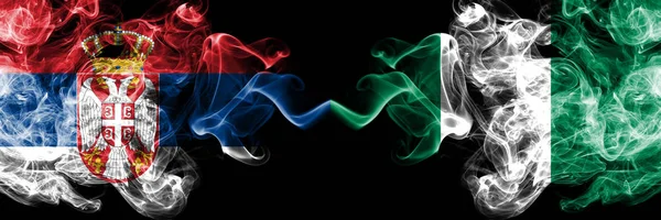 Serbia vs Nigeria, Nigerian smoky mystic flags placed side by side. Thick colored silky smokes combination of Serbian and Nigeria, Nigerian flag