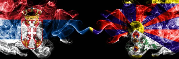 Serbien vs Tibet, tibetanska rökig Mystic flaggor placerade sida vid sida. Tjocka färgade silkeslena röker kombination av serbiska och Tibet, tibetanska flagga — Stockfoto