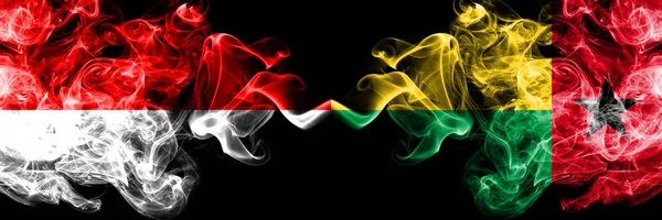 Indonezja vs Gwinea Bissau smoky Mystic flagi umieszczone obok siebie. Grube kolorowe flagi dymu jedwabiste Indonezji i Gwinei Bissau — Zdjęcie stockowe