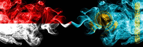 Индонезия vs Казахстан, Казахстан курительные мистические флаги помещены бок о бок. Толстые шёлковые дымовые флаги Индонезии и Казахстана — стоковое фото