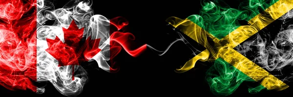 Canada vs Giamaica, bandiere mistiche affumicate giamaicane affiancate. Bandiere di fumo spesse colorate e setose di Canada e Giamaica, Giamaicana . — Foto Stock