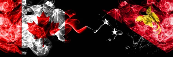 Kanada vs Papua Nya Guinea rökig Mystic flaggor placerade sida vid sida. Tjocka färgade silkeslen rök flaggor kanadensiska och Papua Nya Guinea. — Stockfoto