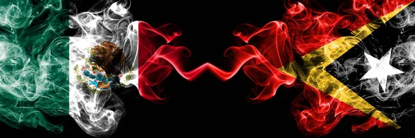 Meksika vs Doğu Timor dumanlı mistik bayraklar yan yana yerleştirilir. Kalın renkli ipeksi soyut Meksika ve Doğu Timor afiş dumanlar