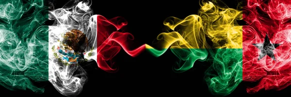 Meksika vs Gine Bissau dumanlı mistik bayraklar yan yana yerleştirilir. Kalın renkli ipeksi soyut Meksika ve Gine Bissau afiş dumanlar