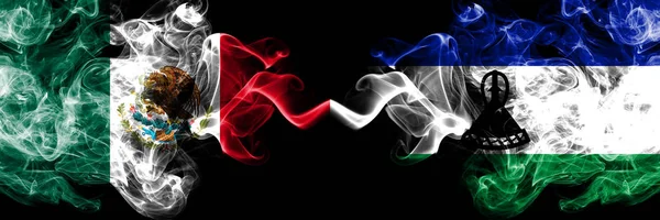 Meksika vs Lesotho dumanlı mistik bayraklar yan yana yerleştirilir. Kalın renkli ipeksi soyut Meksika ve Lesotho afiş dumanlar