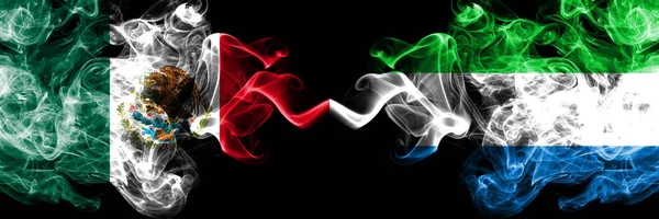 Meksika vs Sierra Leone dumanlı mistik bayraklar yan yana yerleştirilir. Kalın renkli ipeksi soyut Meksika ve Sierra Leone afiş dumanlar