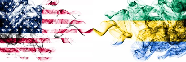Estados Unidos vs Gabón, banderas místicas ahumadas de Gabón colocadas una al lado de la otra. Bandera de humo abstracto sedoso de color grueso de América y Gabón, Gabonés — Foto de Stock