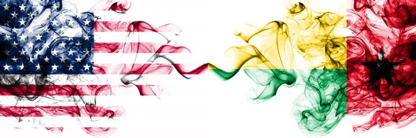 Соединенные Штаты Америки против Гвинеи Бисау курительные мистические флаги помещены бок о бок. Толстые цветные шелковистые абстрактные курит знамя Америки и Гвинеи Бисау — стоковое фото