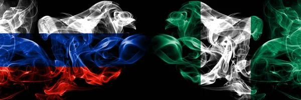 Rusya, Rusya, Nijerya, Nijerya'nın dumanlı mistik bayrakları yan yana yerleştirildi. Kalın renkli ipeksi dumanlar bayrak kavramı — Stok fotoğraf