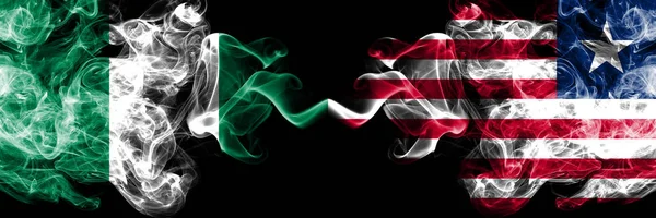 Нигерия против Либерии, либерийские абстрактные дымящиеся мистические флаги, размещенные бок о бок. Толстые цветные шелковистые флаги Нигерии и Либерии, Либерия — стоковое фото