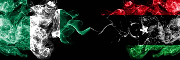 Νιγηρία εναντίον Λιβύης, Λίβυος αφηρημένη καπνιστή μυστικιστική σημαίες τοποθετούνται δίπλα-δίπλα. Χοντρές χρωματιστές μεταξένιες σημαίες καπνού Νιγηρίας και Λιβύης, Λιβύης — Φωτογραφία Αρχείου