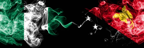 Nigérie vs Papua Nová Guinea abstraktní kouřové mystické vlajky umístěné vedle sebe. Silné barevné hedvábné kouřové vlajky Nigérie a Papuy-Nové Guineje — Stock fotografie