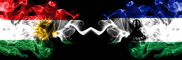 Kurdistan vs Lesotho smoke flags placed side by side. Thick colo — Stock Photo, Image