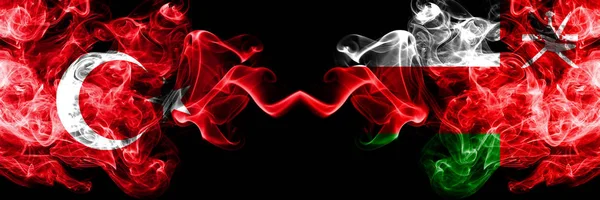 Туреччина проти Оману, оманські димові прапори розміщені пліч-о-пліч. Товстий колір шовковий дим Прапори турецьких і Оман, Омані — стокове фото