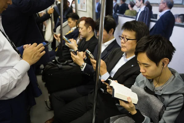 Folk i tunnelbanan använder smartphones och läsa böcker i Tokyo — Stockfoto