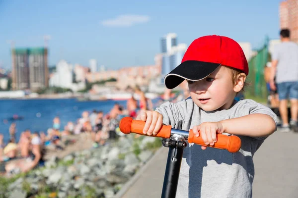 Liten pojke som rider en skoter på vallen i Vladivostok — Stockfoto