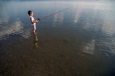 Küçük bir çocuk gölde balık yakalar..