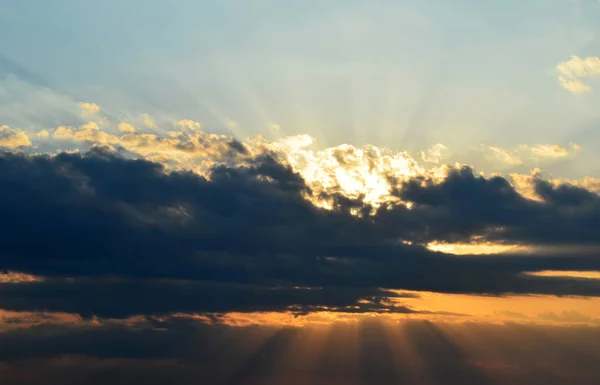 Sunbeams behind large dark cloud on sky at evening — Stock Photo, Image