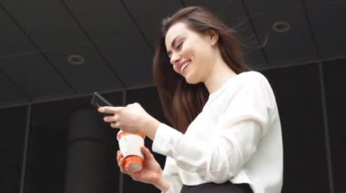 Sıcak içecek smartphone kullanarak ile gülümseyen iş kadını