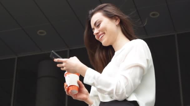 Mujer de negocios sonriente con bebida caliente usando teléfono inteligente — Vídeos de Stock