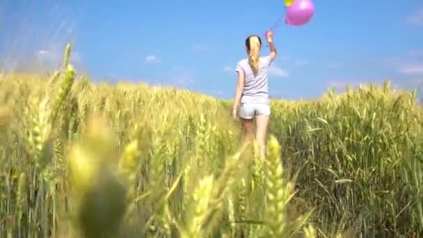 Жінка-підліток з повітряними кулями, що ходять у полі — стокове відео