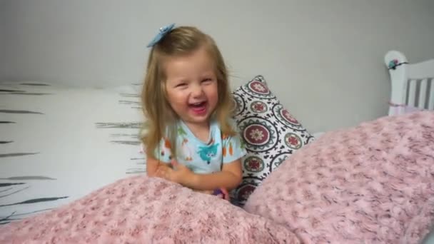 Весела дівчина сидить серед подушок — стокове відео