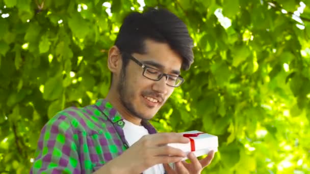 Asiatique homme ouverture cadeau dans le parc en été — Video